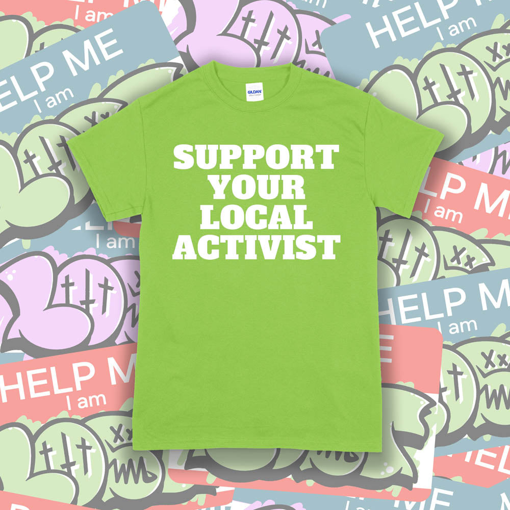 The original Support Your Local Activist t-shirt. Bold white letters screen printed on a lime green shirt. The shirt is displayed against a wall of colorful graffiti stickers.