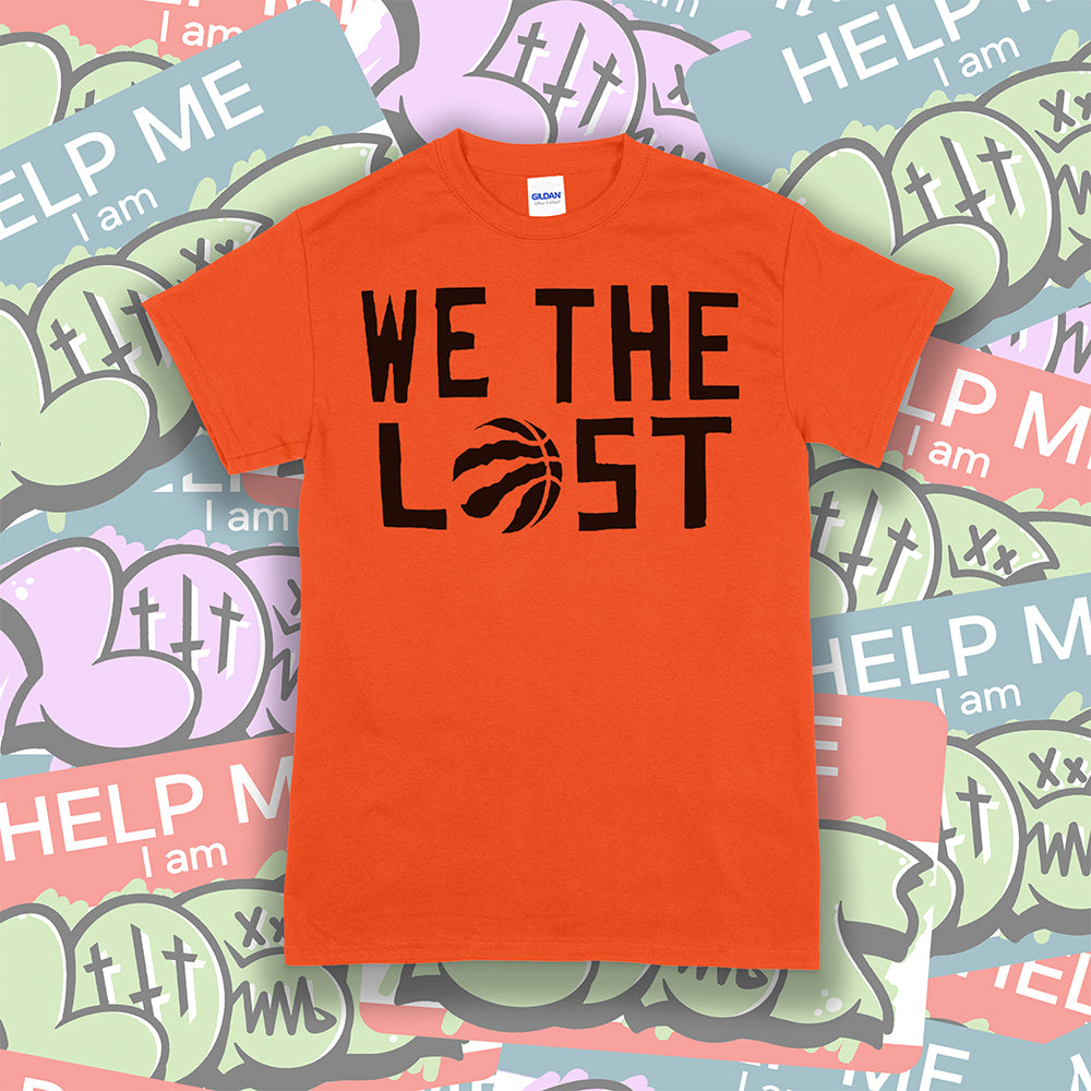 We The Lost t-shirt. Bold black lettering screen printed on a bright orange shirt. Assorted colorful graffiti stickers make up the background.
