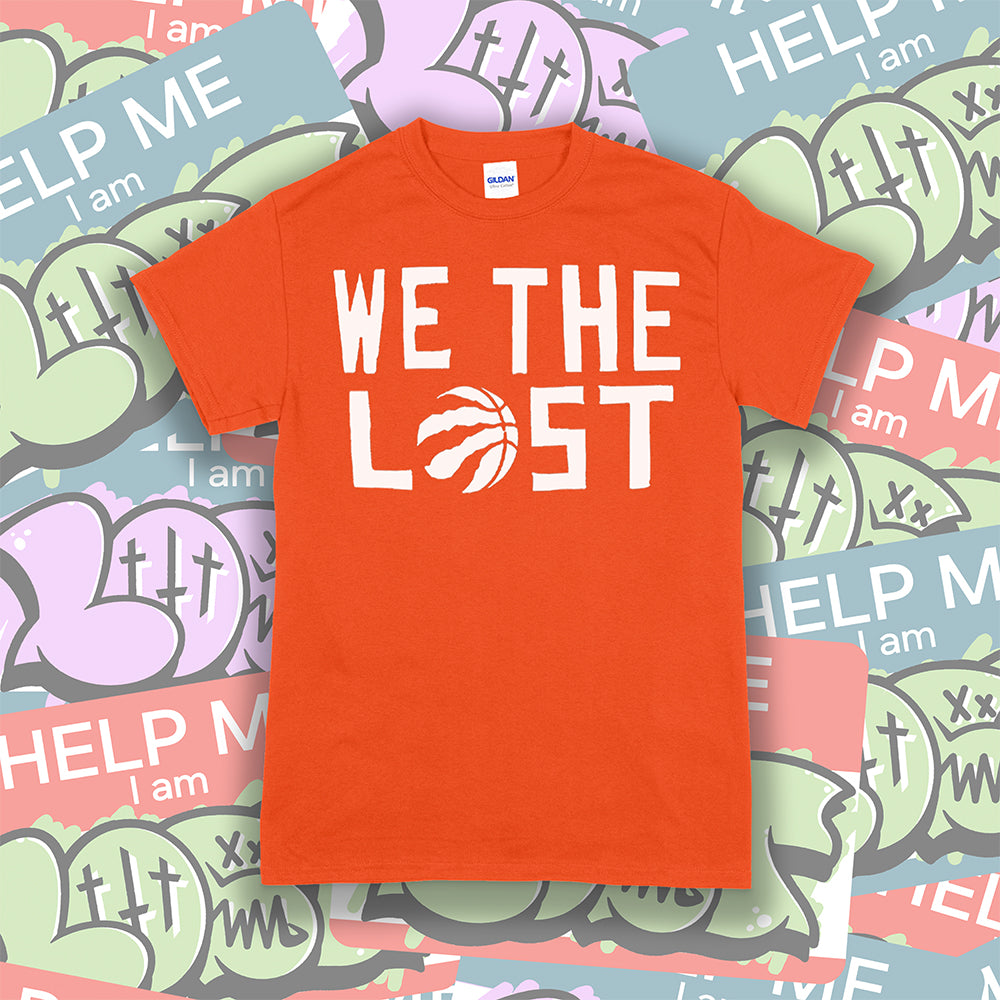 The We The Lost t-shirt. Bold white lettering and raptor claw design screen printed onto an orange colored shirt. A collection of brightly colored graffiti stickers makes up the background.