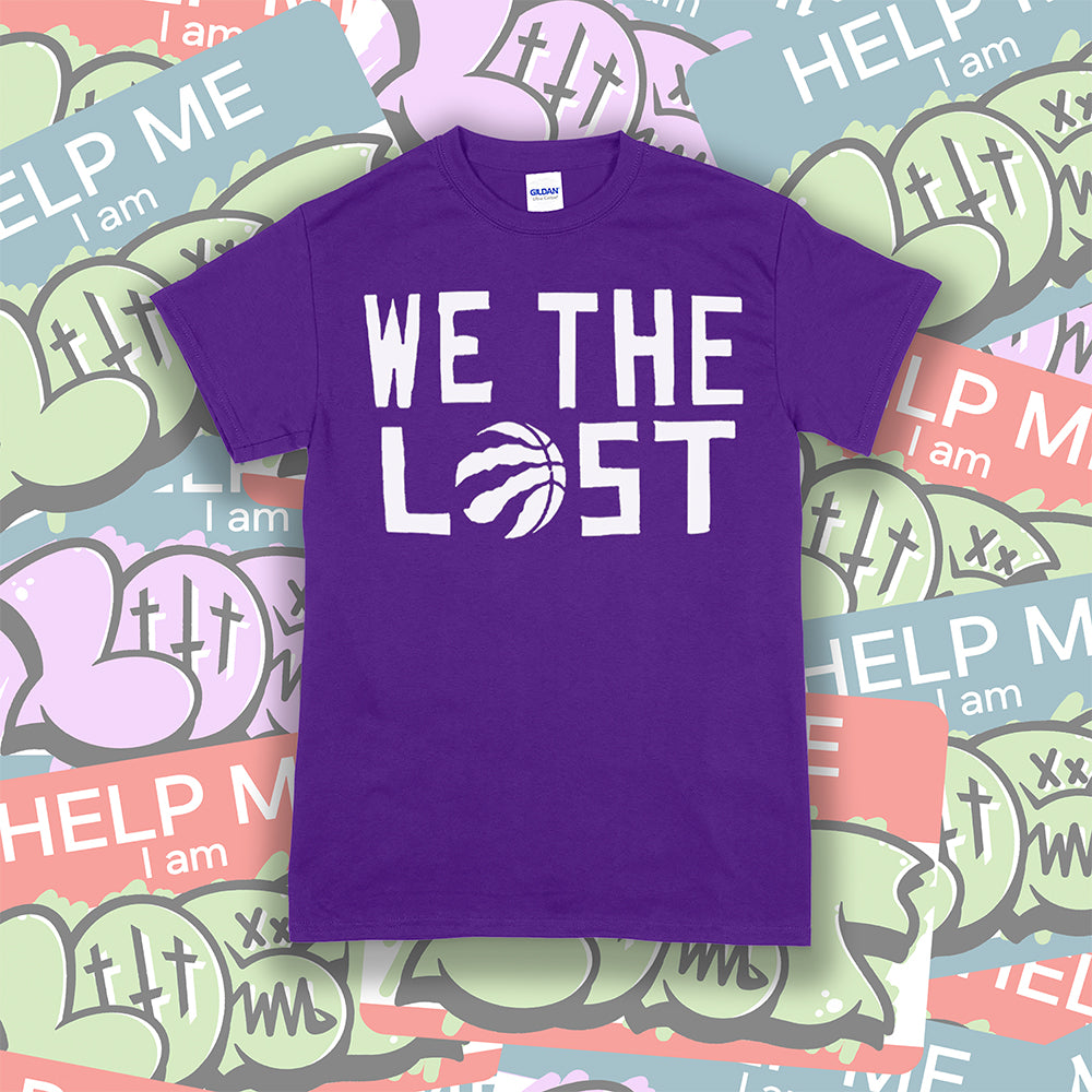 The We The Lost t-shirt. Bold white lettering and raptor claw design screen printed onto a purple colored shirt. A collection of brightly colored graffiti stickers makes up the background.